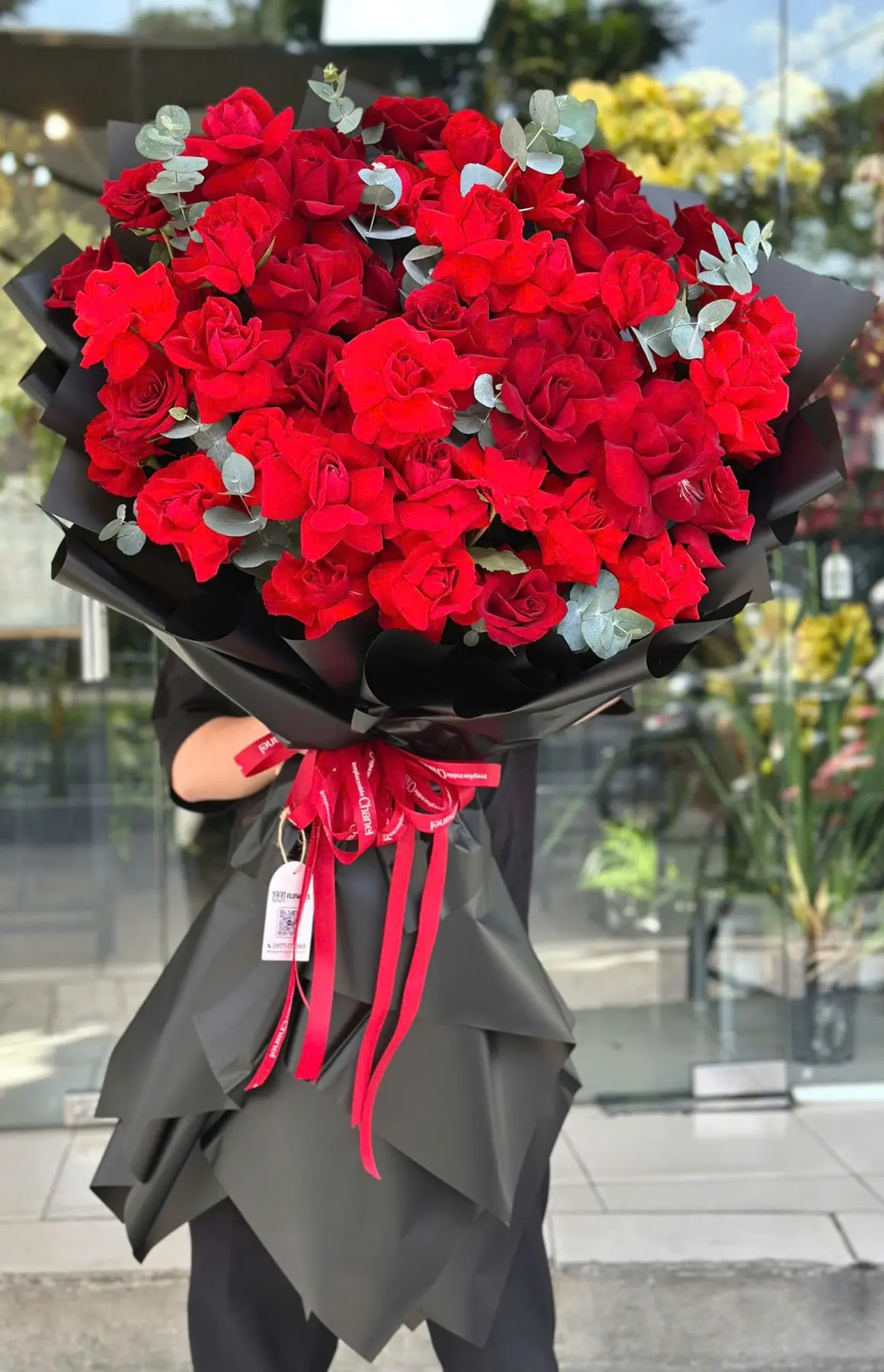 Bó hoa đỏ rực rỡ gói giấy đen sang trọng